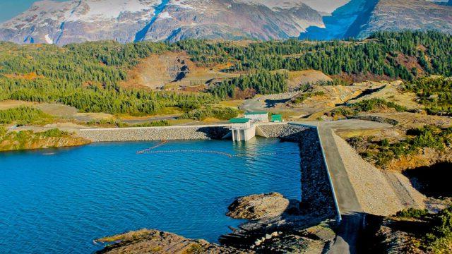 A hydroelectric facility beside a lake and snowy mountains